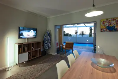 a living room with a dining room table and a television at Die Badhuis, for Fabulous living! Sleeps 4, Private pool in Gordonʼs Bay