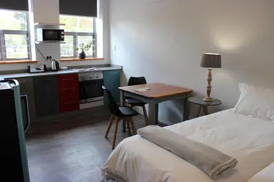a bedroom with a bed and a table and a kitchen at Zeederberg Corner in Paarl
