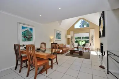 a living room with a wooden table and chairs at Glen Abbey Apartments On The Erinvale Golf And Country Estate in Somerset West