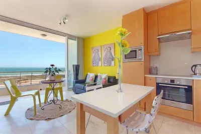 a kitchen and living room with a table and chairs at Neptune Isle 214 in Cape Town