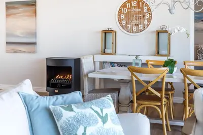a living room with a table and a fireplace at Seapearl Oceanfront Villa and Cottage in Hermanus