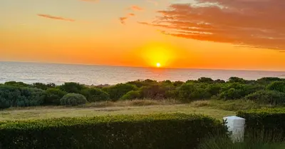 a sunset over the ocean with the sun setting at Seapearl Oceanfront Villa and Cottage in Hermanus
