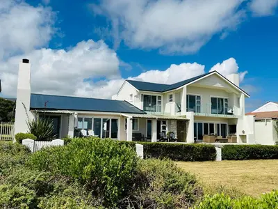 a white house with a blue roof at Seapearl Oceanfront Villa and Cottage in Hermanus