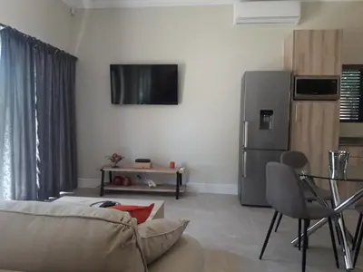 a living room with a couch and a table and a refrigerator at Cottage@Somerset in Somerset West