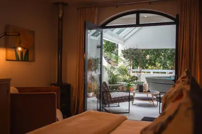 a bedroom with an open door to a patio at Le Petit Manoir Boutique Hotel in Franschhoek