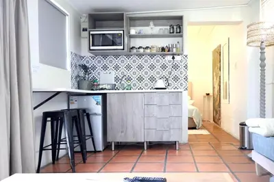 a kitchen with a counter and stools in a room at Courtyard Studio lights and wi fi during load shedding in Stellenbosch