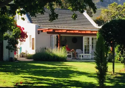 a person sitting on a chair on the porch of a house at Acorn Cottage Hermanus in Hermanus