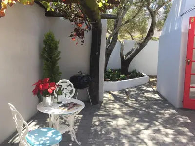 a patio with a table and chairs and a tree at Acorn Cottage Hermanus in Hermanus