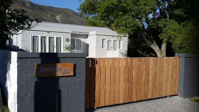 a house with a wooden gate and a fence at Corban Cottage in Hermanus