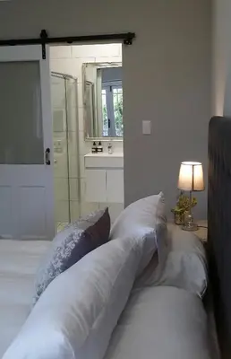 a bedroom with a bed with pillows and a mirror at Corban Cottage in Hermanus