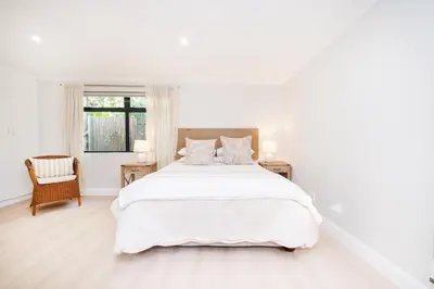 a white bedroom with a large bed and a chair at 10VDW Self Catering Apartments-Newly Renovated! in Durbanville