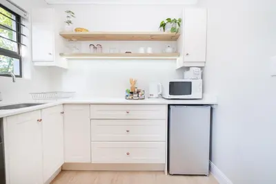 a white kitchen with white cabinets and a microwave at 10VDW Self Catering Apartments-Newly Renovated! in Durbanville