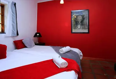 a red bedroom with two beds with towels on them at Orange-Ville Lodge & Guesthouse in Stellenbosch