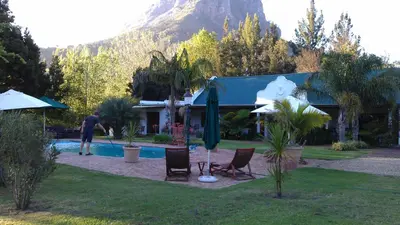 a man standing in front of a house with a pool at Orange-Ville Lodge & Guesthouse in Stellenbosch