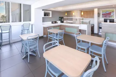 a restaurant with tables and chairs and a kitchen at SUN1 MILNERTON in Cape Town