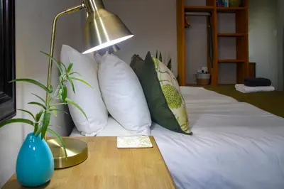 a bed with white pillows and a lamp on a table at Olive tree private rooms in Stellenbosch- No Load Shedding in Stellenbosch