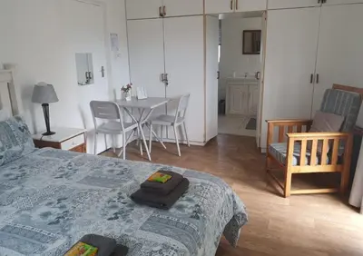 a bedroom with a bed and a table and chairs at 19 on Robyn in Durbanville