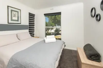 a white bedroom with a bed and a window at 63 Whalerock Estate in Hermanus