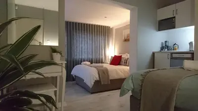 a small bedroom with a bed and a window at Hamilton Garden Suites in Parklands