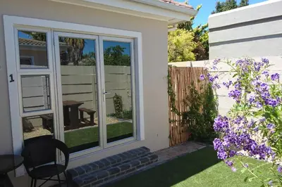 a garden with a window and purple flowers at Hamilton Garden Suites in Parklands