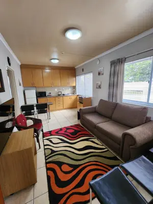 a living room with a couch and a kitchen at 80 Kendal Self-Catering Guest House in Bellville