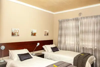 a bedroom with two beds and a window at 80 Kendal Self-Catering Guest House in Bellville