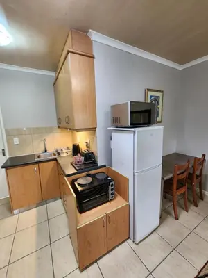 a small kitchen with a white refrigerator and a microwave at 80 Kendal Self-Catering Guest House in Bellville