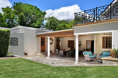 a house with a patio with chairs and tables at The Coach House in Franschhoek