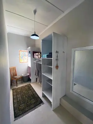 a room with a closet and a table and a chair at Olive and Vine Farm Cottage in Franschhoek