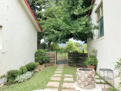 a garden with a tree next to a house at Olive and Vine Farm Cottage in Franschhoek