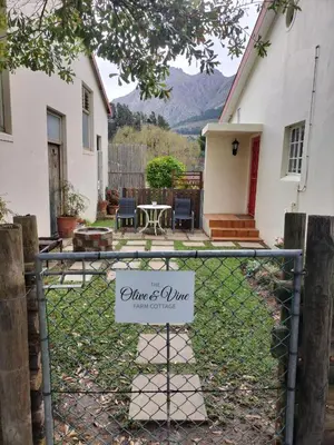 a sign on a fence in front of a house at Olive and Vine Farm Cottage in Franschhoek