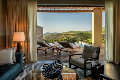 a living room with a couch and chairs and a large window at Delaire Graff Lodges and Spa in Stellenbosch