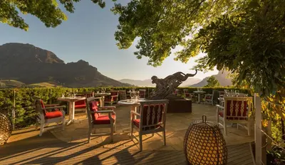 a patio with tables and chairs and a statue at Delaire Graff Lodges and Spa in Stellenbosch