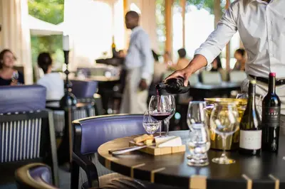 a man pouring wine into a glass on a table at Delaire Graff Lodges and Spa in Stellenbosch