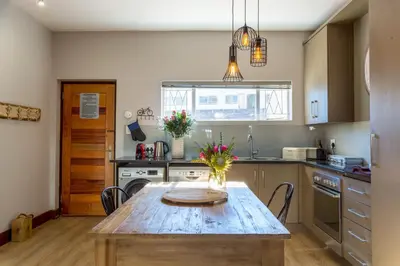 a kitchen with a wooden table with flowers on it at Avemore Vredehof No 3 full back up power in Stellenbosch