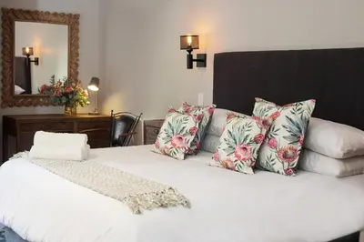a bedroom with a white bed with pillows and a mirror at Avemore Vredehof No 3 full back up power in Stellenbosch