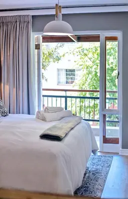 a bedroom with a white bed and a large window at Avemore Jan Cats No 2 full power back up in Stellenbosch