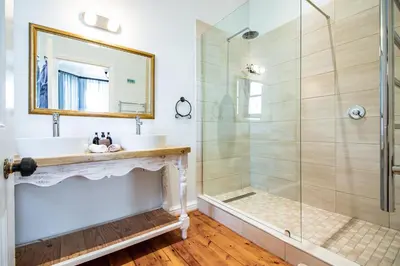 a bathroom with a shower and a sink and a mirror at Carmichael House Boutique Hotel in Cape Town