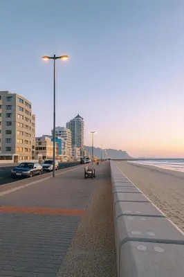 a beach with a bench and buildings and the ocean at Luxurious Beach Front in Strand