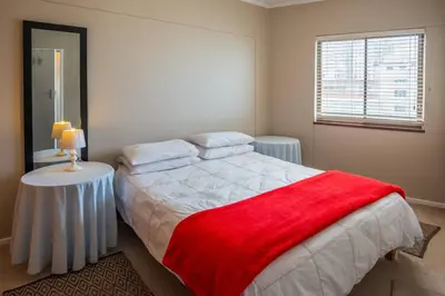 a bedroom with a bed with a red blanket on it at Luxurious Beach Front in Strand