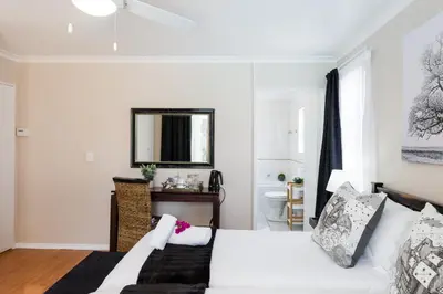a white bedroom with a bed and a mirror at Atlantic Beach Villa in Cape Town