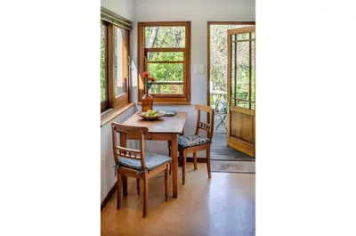 a dining room with a table and chairs and windows at Languedoc in Stellenbosch