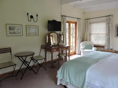 a bedroom with a bed and a desk and a tv at Languedoc in Stellenbosch