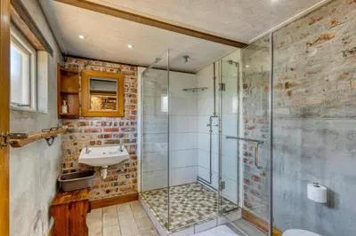 a bathroom with a glass shower and a sink at The Yard in Gordonʼs Bay