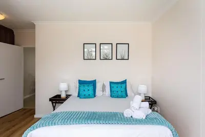 a bedroom with a large white bed with blue pillows at Waterstone A103 by CTHA in Cape Town