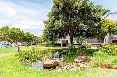 a garden with a waterfall in a yard with a tree at Waterstone A103 by CTHA in Cape Town