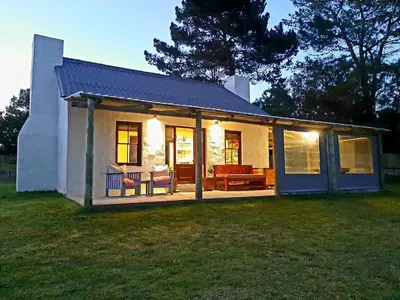 a small house with a porch and a patio at The Cottage at Nuwejaarsrivier Farm in Kleinmond