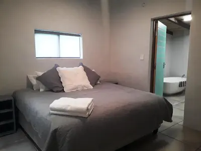a bedroom with a bed with a window and a tub at The Cottage at Nuwejaarsrivier Farm in Kleinmond