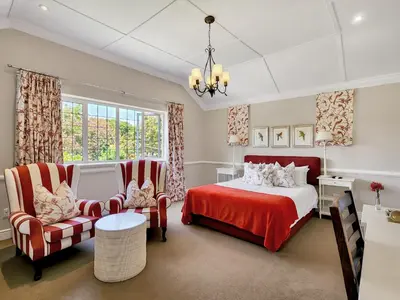 a bedroom with a bed and two chairs at Roodenburg House in Cape Town