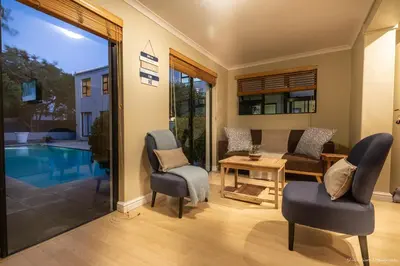 a living room with a pool and two chairs and a table at Atlantic Bay Lodge in Cape Town